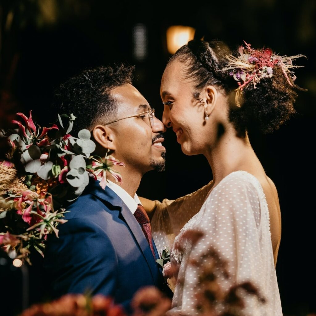 Casal de noivos negros se olhando apaixonadados enquanto sorriem